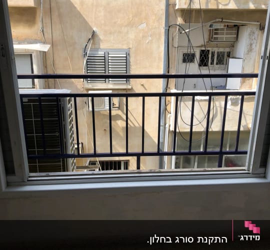 מסגרת חלון עם סורגי מתכת מול בניין סמוך